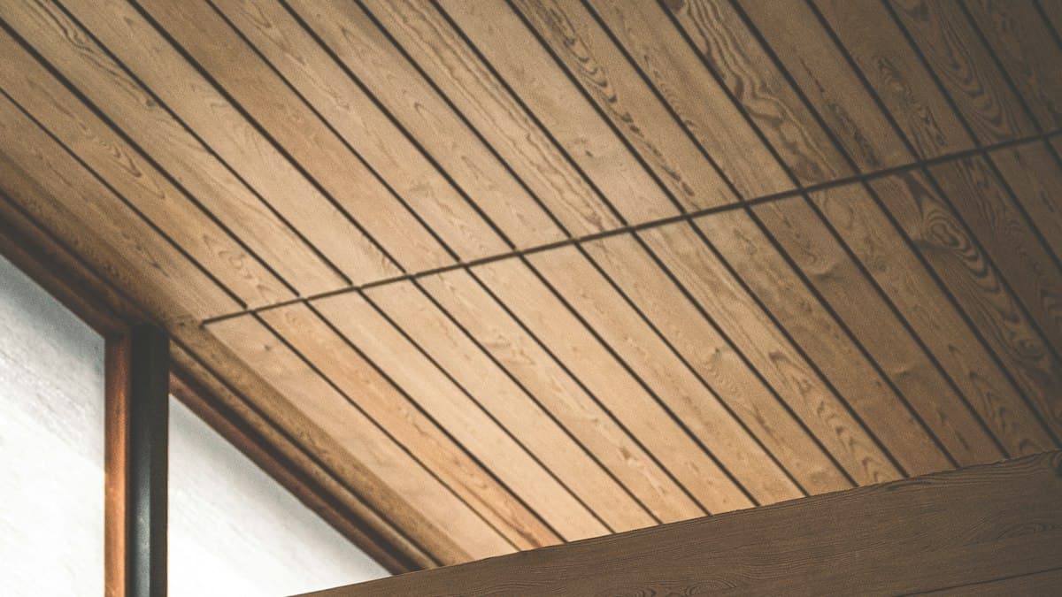 Close-up of an angled wood tongue-and-groove ceiling showing the interlocking plank joint lines