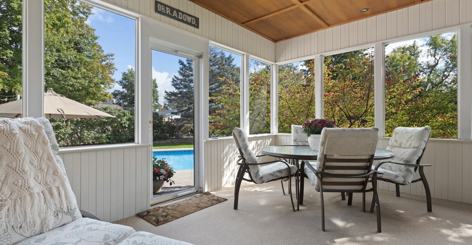 Screened, covered patio with a wood ceiling and dining table overlooking a pool